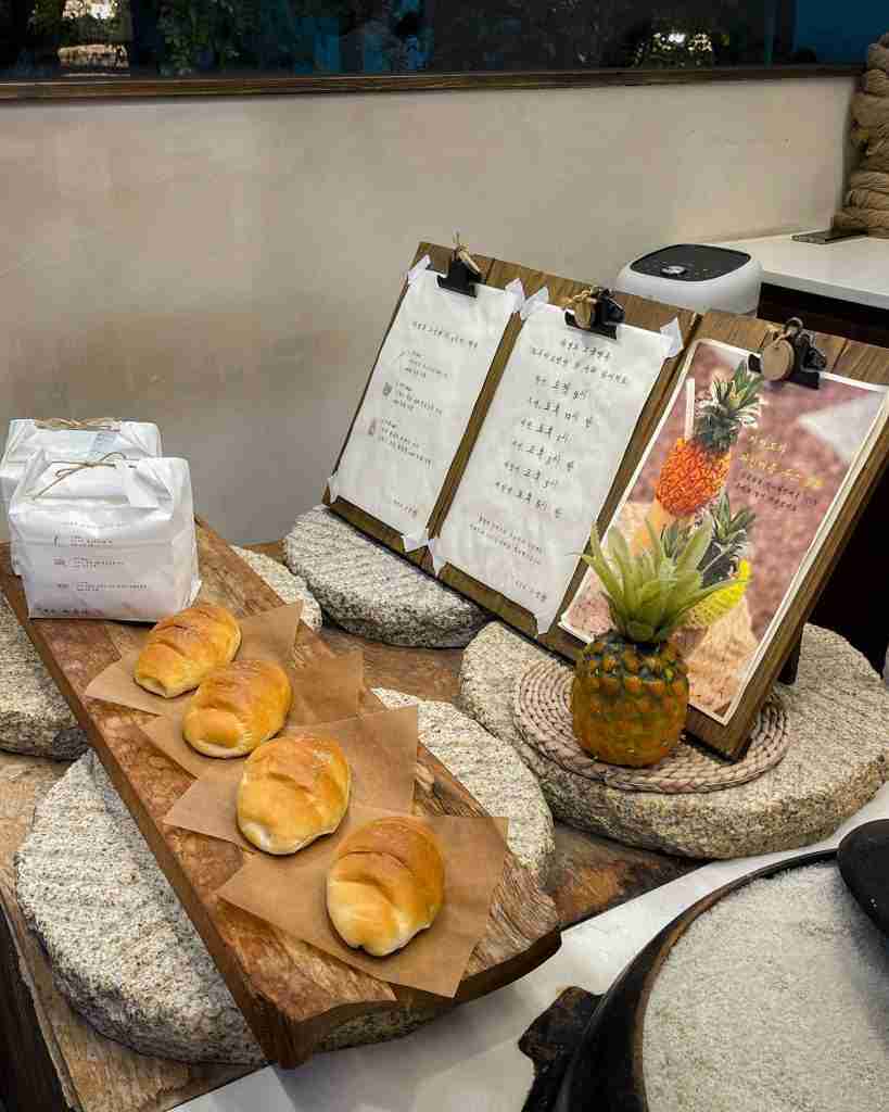 Jayeondo Sogeumppang storefront inside Ikseondong Hanok Village, with four salt bread buns neatly arranged on a piece of wood beside the store menu.