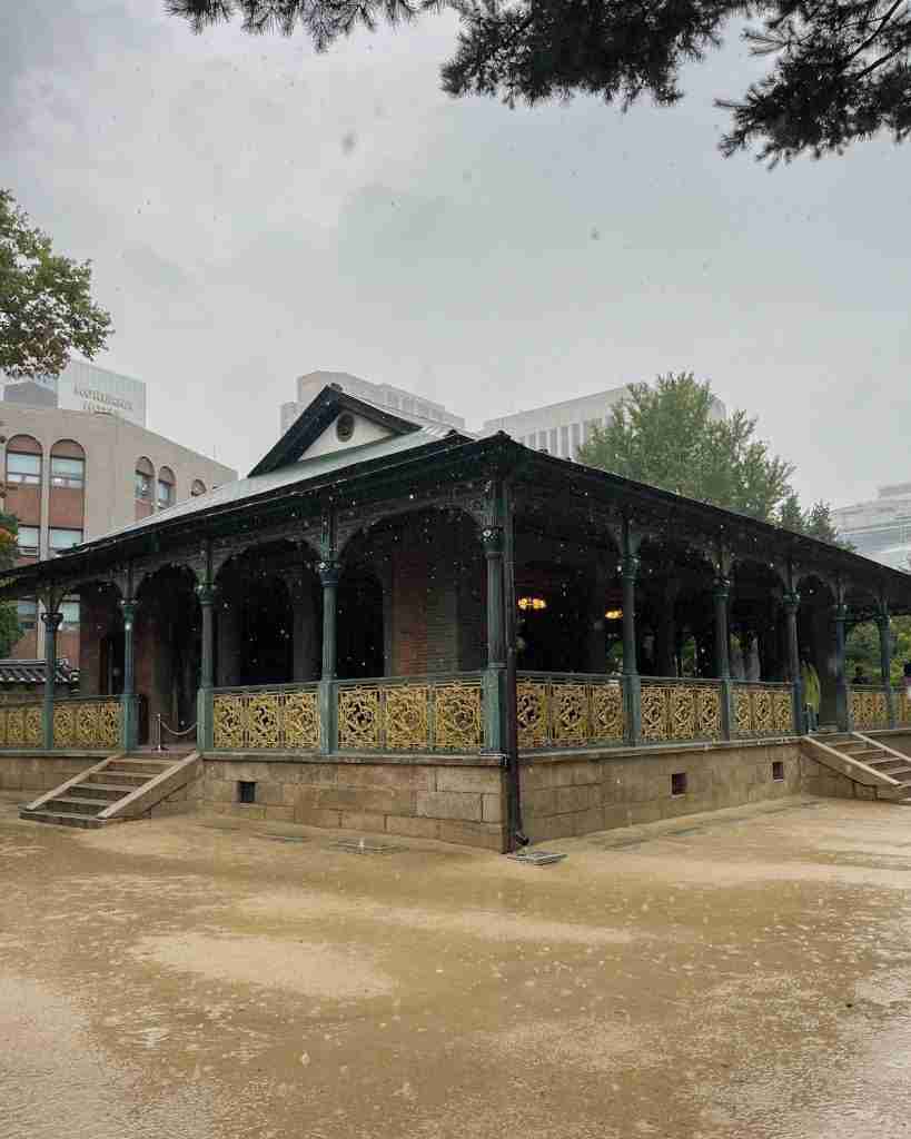The unique Jeonggwanheon pavilion, a blend of traditional Korean architectural style with Western architectural style, in the heavy rain under a gray sky.