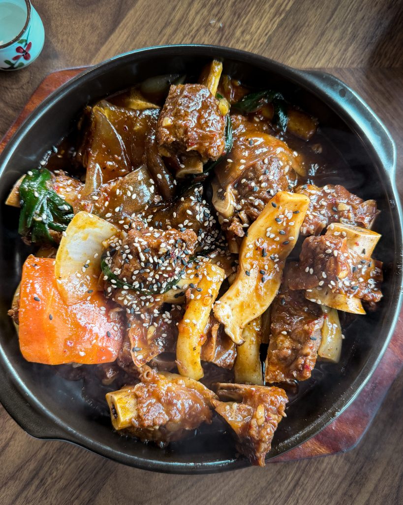 Steaming bowl of spicy gochujang galbijjim with braised beef short ribs, vegetables, and sesame seeds served at Poseok-ro restaurant. This hearty local meal is a popular dinner after a full day of sightseeing in Gyeongju.