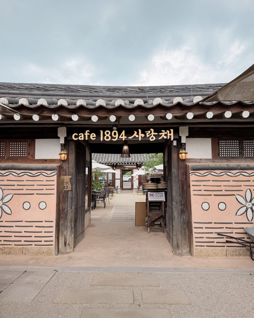 Traditional hanok entrance to Cafe 1894 with an open wooden gate leading into a peaceful courtyard seating area. The cafรฉ sits near Daereungwon Tomb Complex and blends historic Korean architecture with a relaxing atmosphere.
