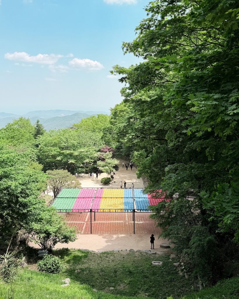 Colorful lanterns and forested hills viewed from the grounds near Seokguram Grotto on Mount Toham. The peaceful mountain setting makes the grotto a rewarding stop before walking downhill to Bulguksa Temple.